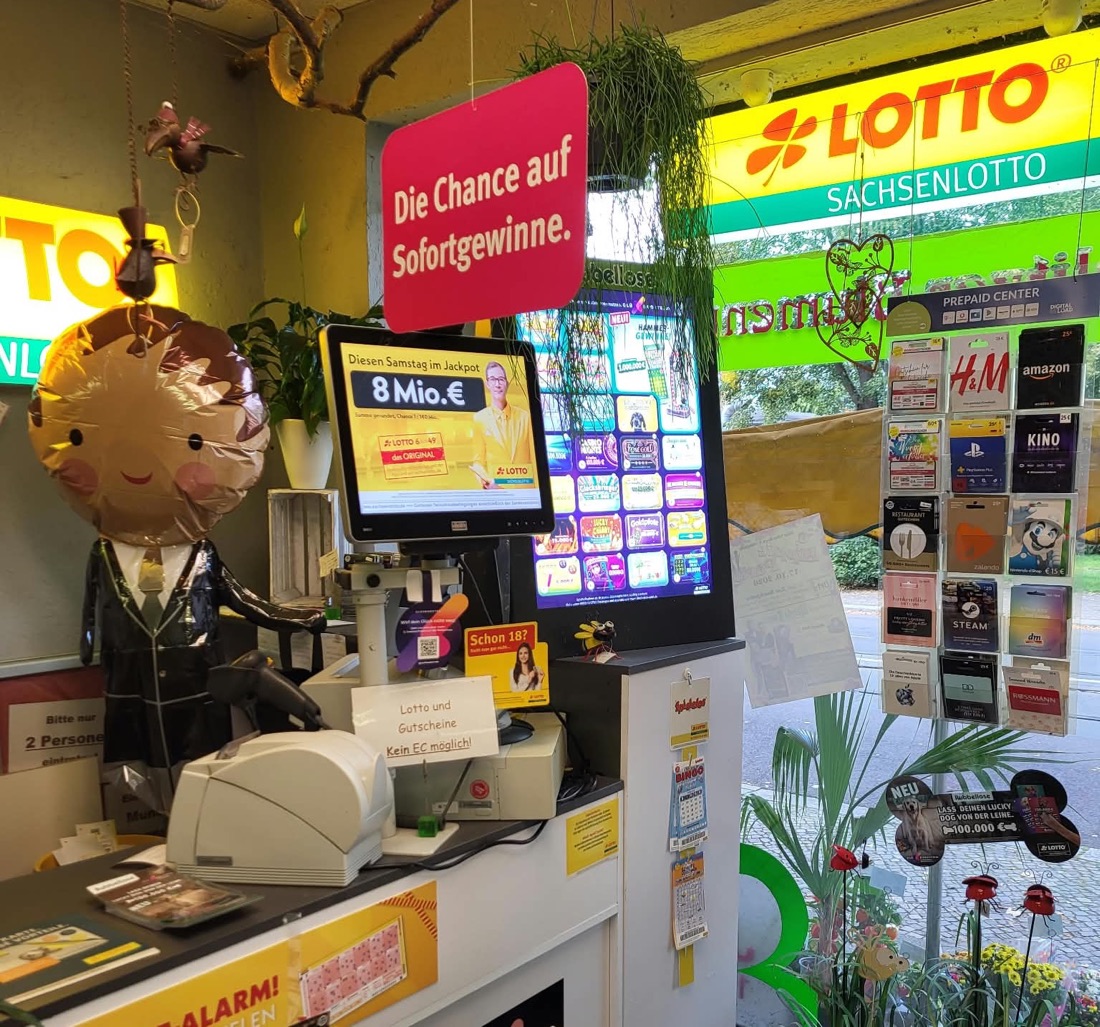 Lotto-Annahmestelle im Laden: Lotto-Terminal, Rubbellos-Bildschirm und ein Ständer mit Geschenkkarten